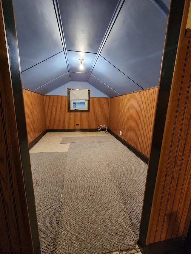 bonus room with lofted ceiling, wood walls, and light colored carpet