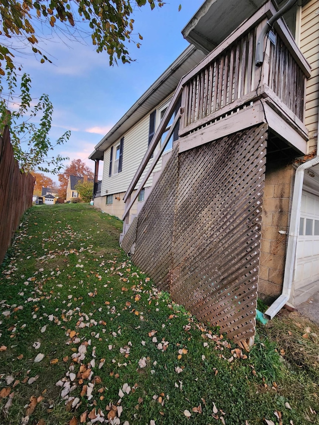 property exterior at dusk with a yard and a garage