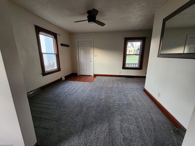 empty room with carpet, ceiling fan, a textured ceiling, and a wealth of natural light