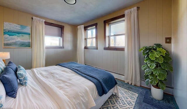 bedroom with carpet flooring, a baseboard heating unit, and wood walls