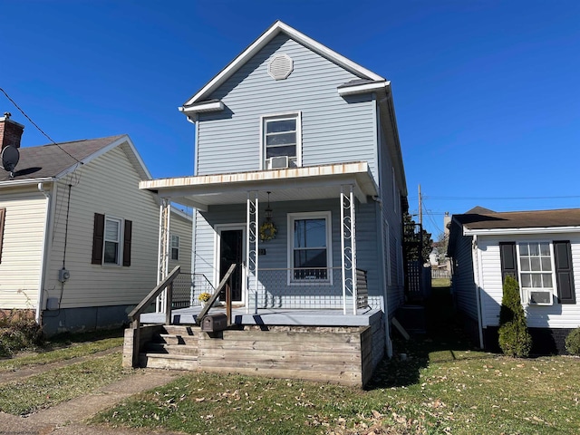 traditional-style home featuring covered porch, cooling unit, and a front yard