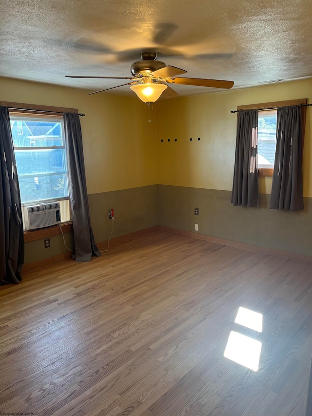 spare room featuring a textured ceiling, ceiling fan, wood finished floors, and cooling unit