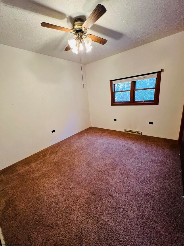 carpeted spare room featuring ceiling fan and a textured ceiling