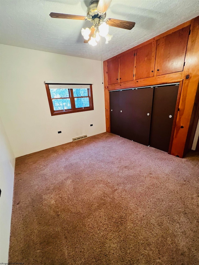 unfurnished bedroom featuring a textured ceiling, carpet floors, a closet, and ceiling fan