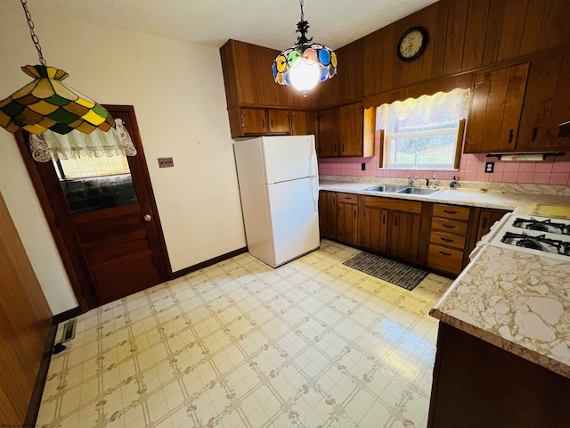 kitchen with decorative light fixtures, sink, backsplash, and white appliances