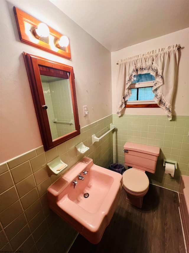 bathroom featuring toilet, wood-type flooring, sink, and tile walls