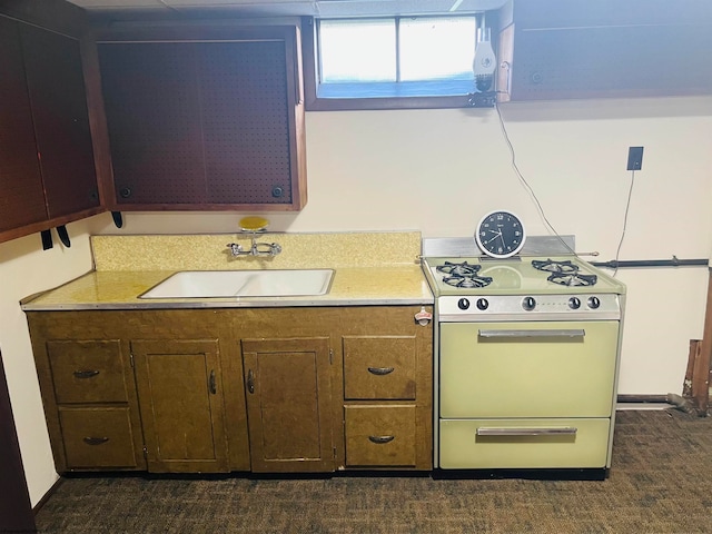 kitchen with stove, sink, and dark colored carpet