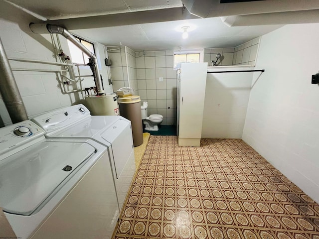 washroom with a healthy amount of sunlight, washing machine and dryer, and gas water heater