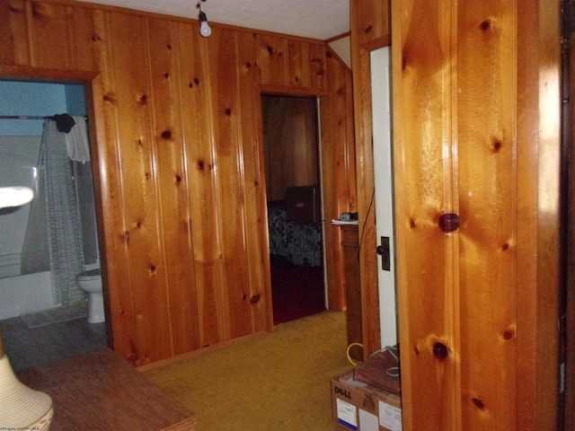 hall featuring carpet floors and wooden walls