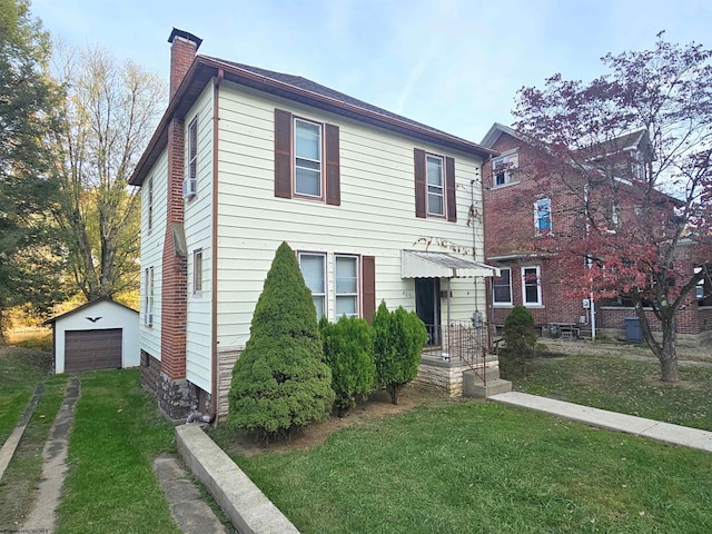 view of front of home with a front yard, a garage, and an outbuilding