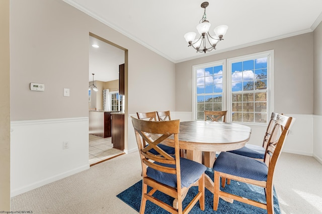 carpeted dining area featuring a notable chandelier and ornamental molding