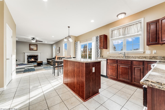 kitchen featuring light tile patterned flooring, a kitchen island, hanging light fixtures, ceiling fan, and stainless steel dishwasher