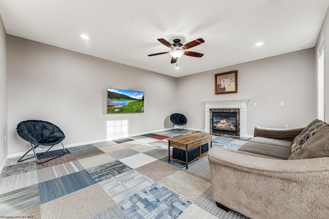 carpeted living room featuring a high end fireplace and ceiling fan