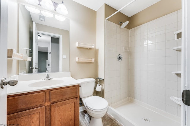 bathroom with a tile shower, toilet, and vanity