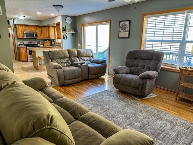 living room featuring sink, ceiling fan, a textured ceiling, and light hardwood / wood-style flooring