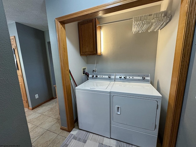 washroom with cabinets, a textured ceiling, washing machine and dryer, and light tile patterned floors