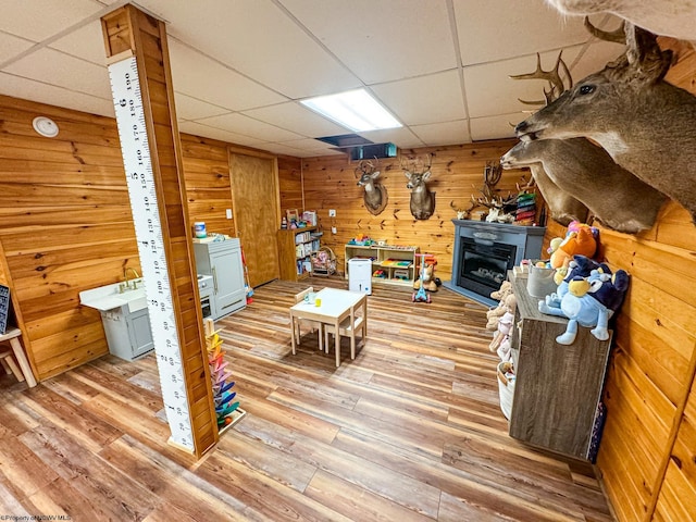 interior space featuring hardwood / wood-style floors, a paneled ceiling, and wood walls