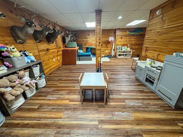 rec room featuring hardwood / wood-style flooring, a drop ceiling, and wooden walls