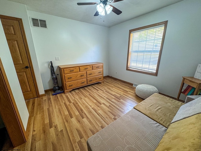 living area with a textured ceiling, light hardwood / wood-style floors, and ceiling fan