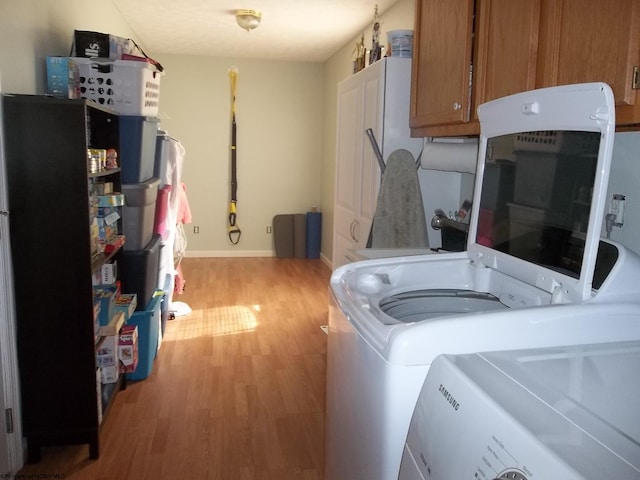 clothes washing area featuring cabinets, light hardwood / wood-style flooring, and separate washer and dryer