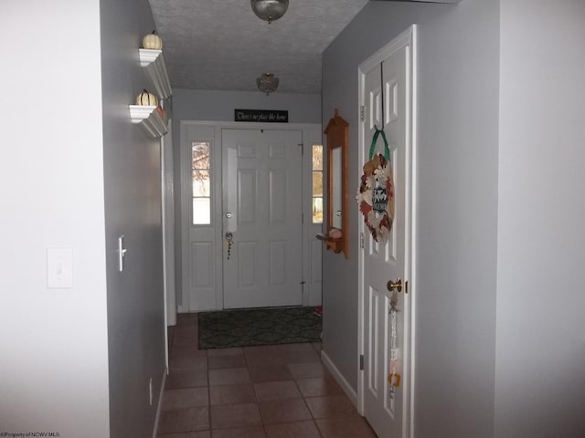 entryway with a textured ceiling and dark tile patterned flooring