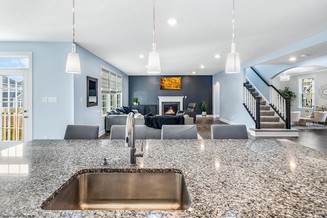 kitchen with stone countertops, hardwood / wood-style flooring, decorative light fixtures, and plenty of natural light