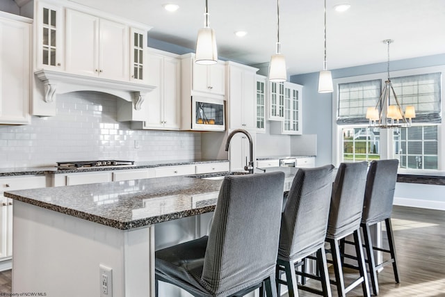 kitchen featuring dark hardwood / wood-style flooring, a kitchen breakfast bar, stainless steel appliances, white cabinets, and a kitchen island with sink