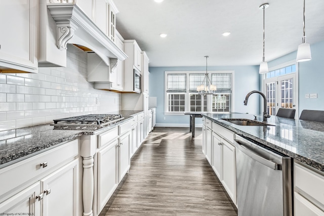 kitchen with appliances with stainless steel finishes, dark hardwood / wood-style floors, sink, and pendant lighting