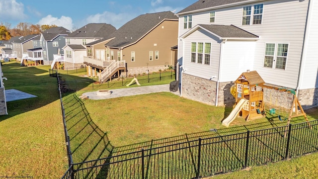 rear view of house with a yard, a deck, and a playground