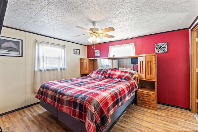 bedroom with wood walls, hardwood / wood-style floors, and ceiling fan