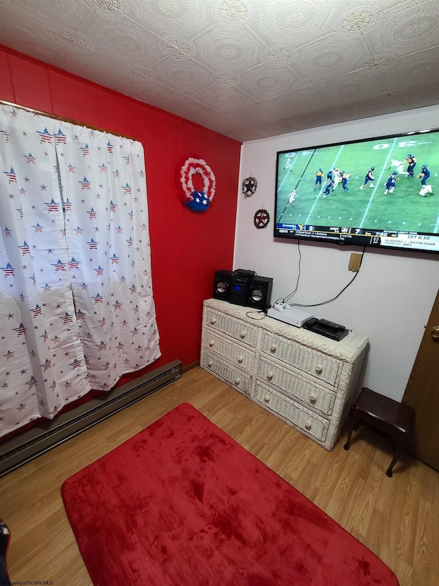 bedroom featuring light hardwood / wood-style floors, a textured ceiling, and a baseboard radiator