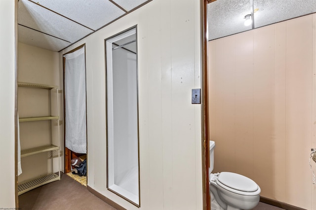 bathroom featuring toilet and wood walls