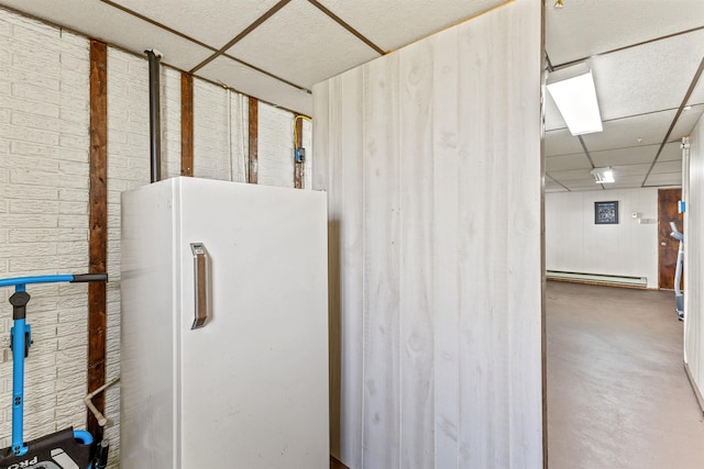 kitchen with a drop ceiling, concrete flooring, a baseboard radiator, and white refrigerator