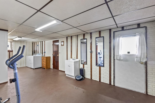 basement featuring brick wall, a paneled ceiling, and separate washer and dryer