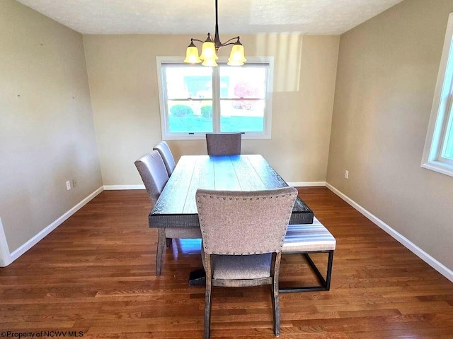 dining area featuring a textured ceiling, dark wood-type flooring, and an inviting chandelier