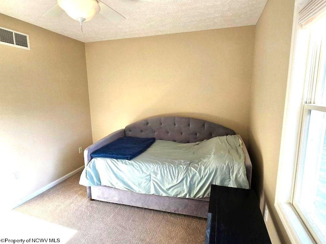 bedroom featuring carpet, a textured ceiling, multiple windows, and ceiling fan