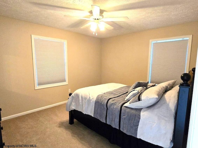 carpeted bedroom featuring ceiling fan and a textured ceiling