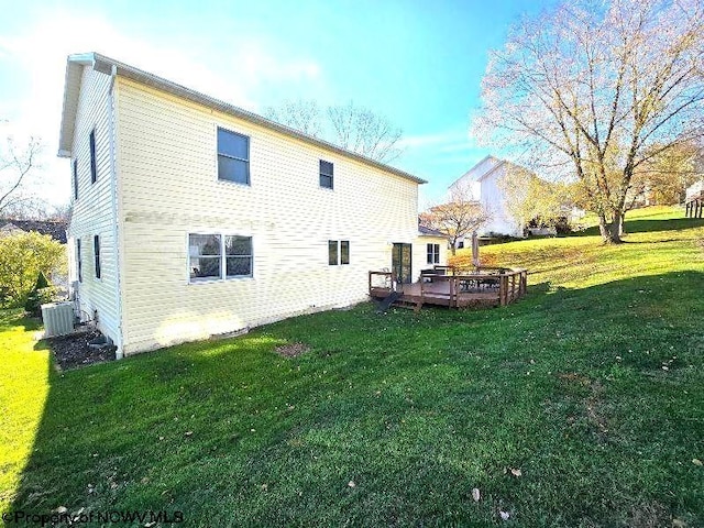 rear view of property featuring cooling unit, a yard, and a wooden deck