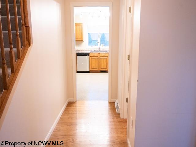 corridor with light wood-type flooring and sink