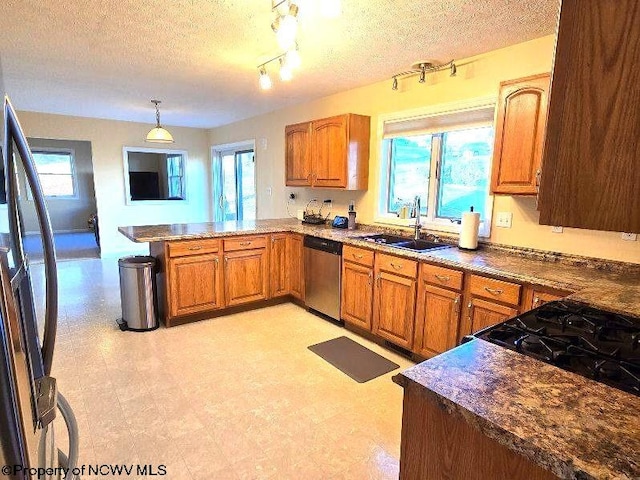 kitchen with a textured ceiling, refrigerator, stainless steel dishwasher, and plenty of natural light