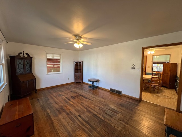 empty room with ceiling fan, a wealth of natural light, and dark hardwood / wood-style flooring