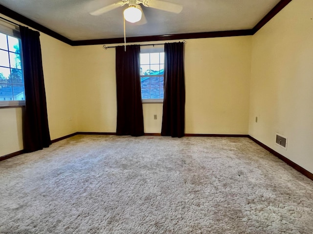 carpeted empty room with crown molding, a wealth of natural light, and ceiling fan