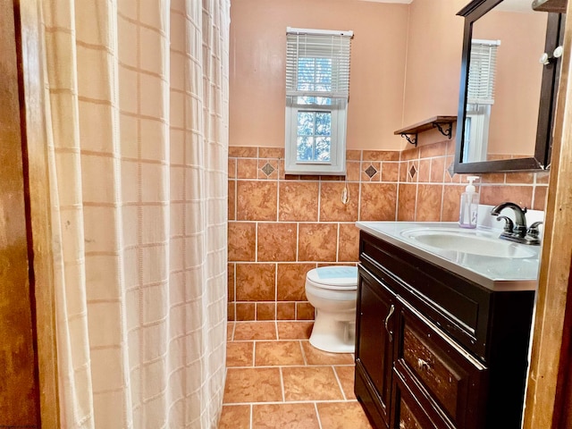 bathroom with tile patterned floors, toilet, a shower with curtain, vanity, and tile walls