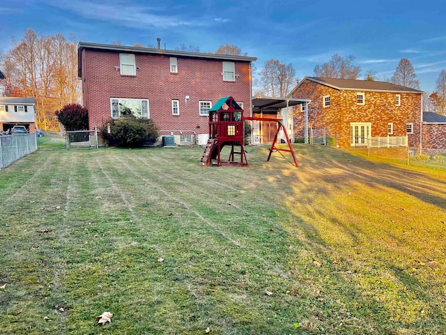 back of house featuring a playground, central AC unit, and a lawn