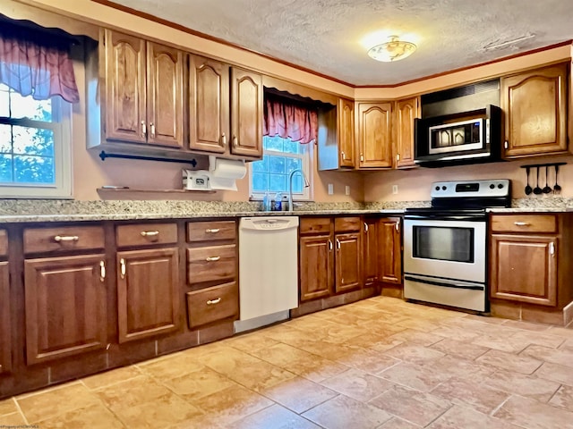 kitchen with sink, appliances with stainless steel finishes, light stone counters, and a textured ceiling