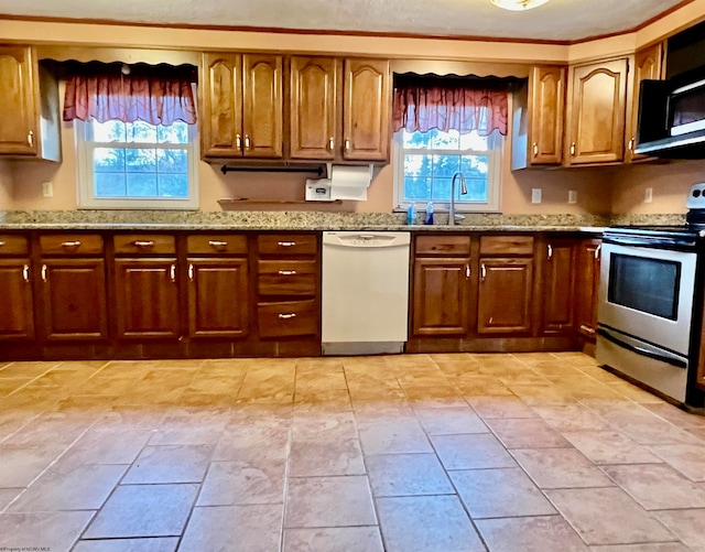 kitchen featuring white dishwasher, sink, light stone countertops, and stainless steel range with electric cooktop