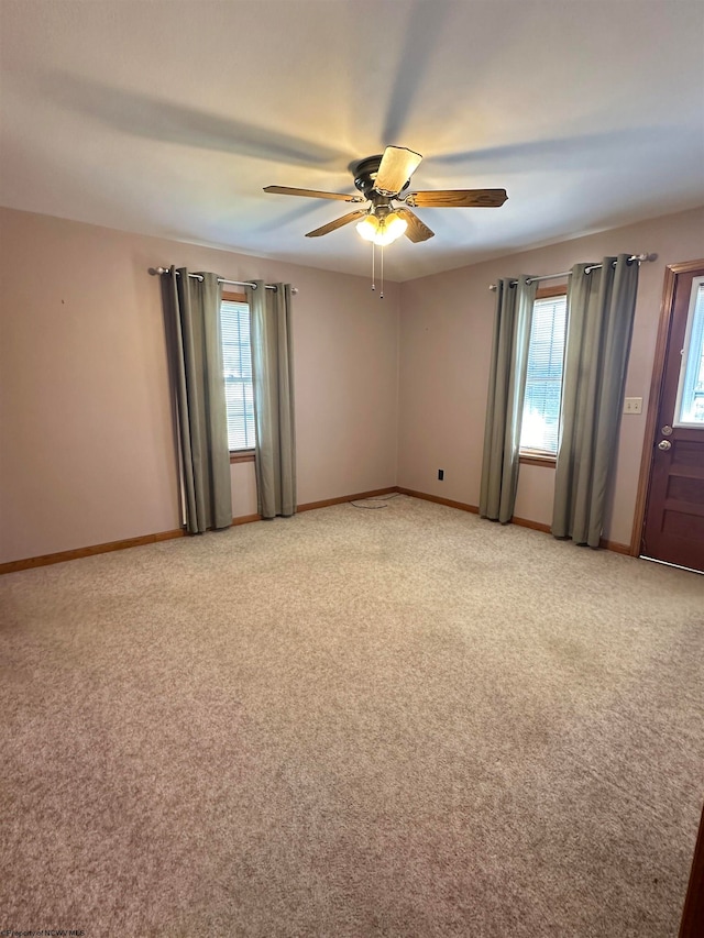 carpeted empty room featuring plenty of natural light and ceiling fan