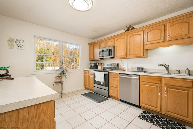 kitchen with sink, light tile patterned floors, and stainless steel appliances