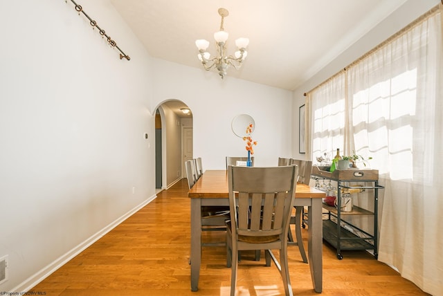 dining area with an inviting chandelier, lofted ceiling, and wood-type flooring