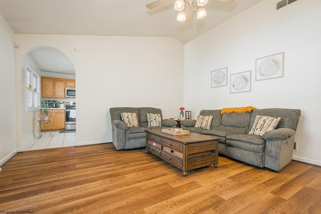 living room with ceiling fan, light hardwood / wood-style flooring, and lofted ceiling